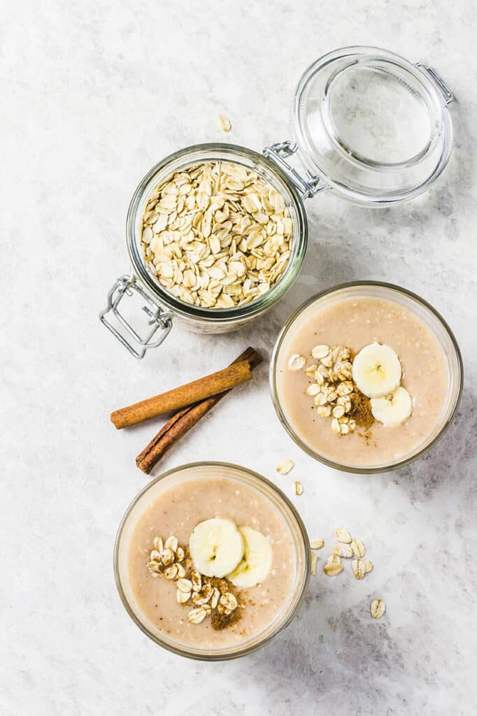 Banana Smoothie with peanuts oats and garnished with banana on a light marble background