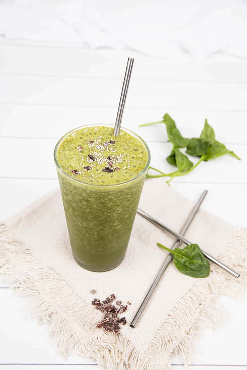 Meal Replacement Smoothie on a white background, green with cocao nibs as garnish