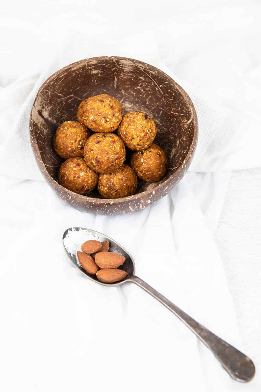 Carrot cake Bliss balls in a coconut bowl on a white background