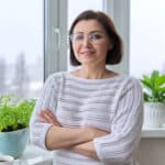 Denise Wright Profile Pic, Middle age lady with brown hair, white jumper in the loungeroom
